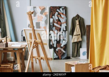 Worplace of modern artist with canvas on wooden easel standing in the center of spacious studio or classroom of school of arts Stock Photo