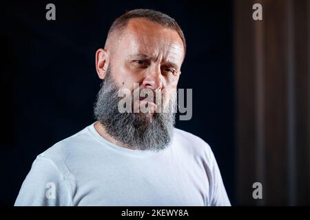 Emotional portrait of an adult gray-haired man with a beard in a white t-shirt Stock Photo