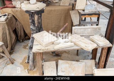 horizontal view of a stonte workshopwhere objects carved and tools for their elaboration are shown Stock Photo