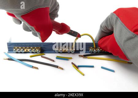 An electrician in protective gloves bites the jumper of an electric cable with wire cutters Stock Photo