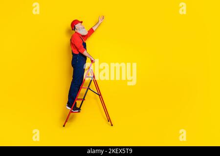 Full size profile side photo of senior workman use tool stepladder change lamp bulb isolated on bright color background Stock Photo