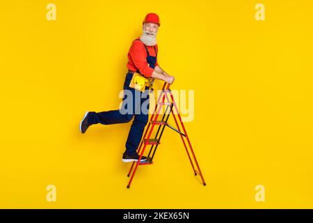 Full size photo of retired senior technician climb ladder installing lamp light isolated on bright color background Stock Photo