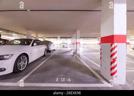 A garage with parked cars, free spaces and columns with warning signs Stock Photo