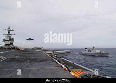 An F/A-18F Super Hornet, attached to the 'Blacklions' of Strike Fighter Squadron (VFA) 213, conducts a fly-by of the first-in-class aircraft carrier USS Gerald R. Ford (CVN 78) as Sailors assigned to the Dutch frigate HNLMS De Even Provincien (F 802) observe flight operations, Nov. 12, 2022. Exercise Silent Wolverine is a U.S.-led, combined training exercise that tests Ford-class aircraft carrier capabilities through integrated high-end naval warfare scenarios alongside participating allies in the Eastern Atlantic Ocean. The Gerald R. Ford Carrier Strike Group is conducting their first deploym Stock Photo