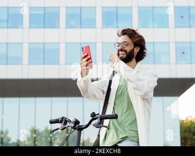 Young italian businessman with a bike making a video call with a smartphone. Young enterprising man Stock Photo