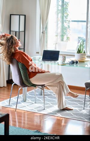 Young smiling pretty woman relaxing at home sitting at table. Vertical Stock Photo