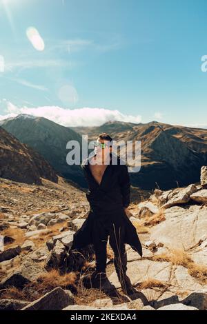 Boy taking off his jacket while climbing a mountain path Stock Photo