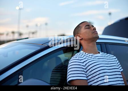 Tired man while leaning on car at sunset Stock Photo