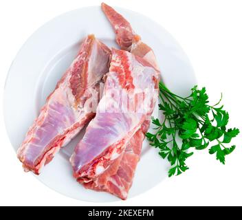 Raw meaty pork ribs slabs on plate with fresh greens Stock Photo