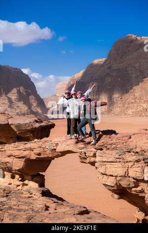 Four female tourists posing on rock bridge Wadi Rum Jordan Stock Photo