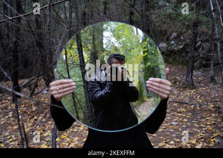 photographer photo shooting a girl holding a mirror in forest Stock Photo