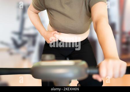 Shot of a young woman exercising at the gym on a stationary bike and measuring her fats Stock Photo