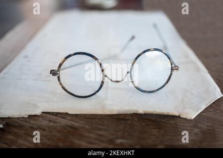 Close up old spectacles on a paper on a wooden desk Stock Photo