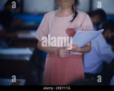 Teacher controls the exam room for students to take the exam in the classroom with wearing facemask for protection covid-19 Stock Photo
