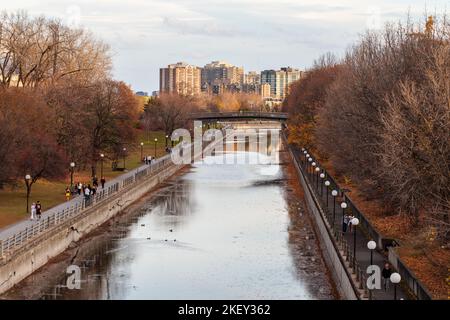 Ottawa, Canada - November 5, 2022: Rideau Canal in autumn season in park with pathway, bike lane with walking people and buildings Stock Photo