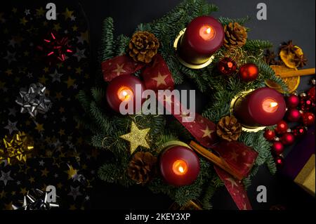 Top down view of advent wreath with lit candles surrounded by christmas decor Stock Photo