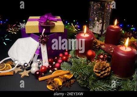 Mask and COVID test kit leaning on gift box next to advent wreath and snow globe Stock Photo
