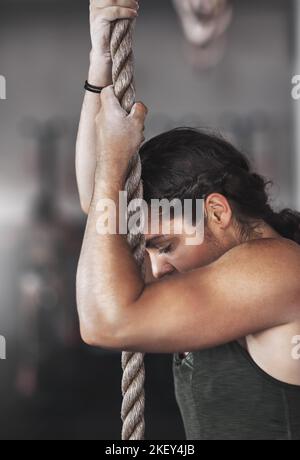 Theres no easy way to the top. a young woman climbing a rope at the gym. Stock Photo