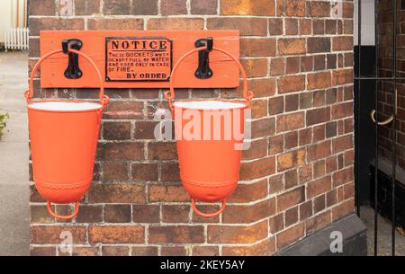 two red fire buckets hanging on a wall, vintage fire fighting equipment Stock Photo