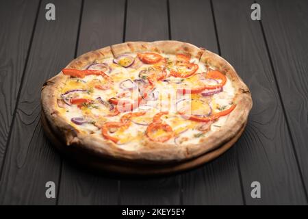 Fresh Homemade Italian Pizza with red onion, pepper, mozzarella and bacon on black background Stock Photo