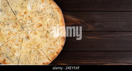 Delicious sliced pizza Four Cheeses with cheddar, Parmesan, mozzarella and tomato sauce on wooden background. View from above. Stock Photo