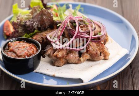 Healthy barbecue lean cubed pork kebabs served with a fresh lettuce, onion and tomato sauce, close up view Stock Photo