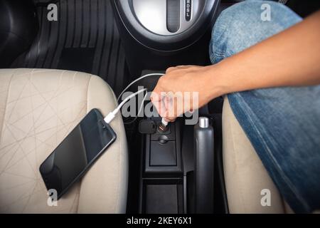 Charging smartphone battery with usb charger in the car. Stock Photo