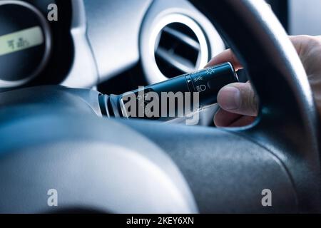 Driver turn on the headlight in a car. Close up at car light switch. Stock Photo