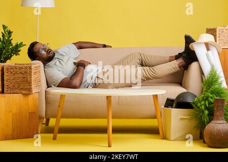 Tired man fell asleep on sofa after dinner Stock Photo