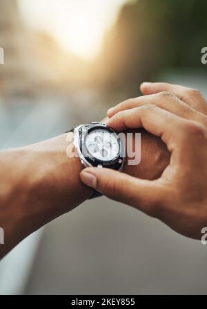 Time to cover some miles. a runner checking his sports watch while training. Stock Photo