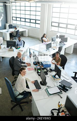 Looking down at the company professionals. High angle shot of a group of colleagues working on computers in an office. Stock Photo