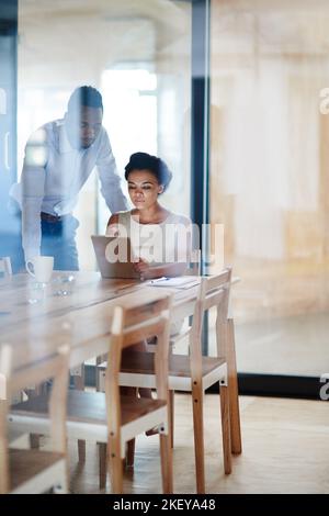 Working together to ensure success. colleagues using a digital tablet together in an office. Stock Photo