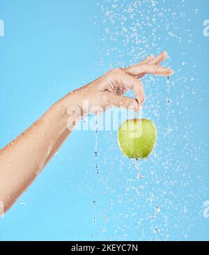 Water, splash and hand with apple in studio for health, nutrition and wellness. Natural diet, healthy eating and person holding fruit with water Stock Photo