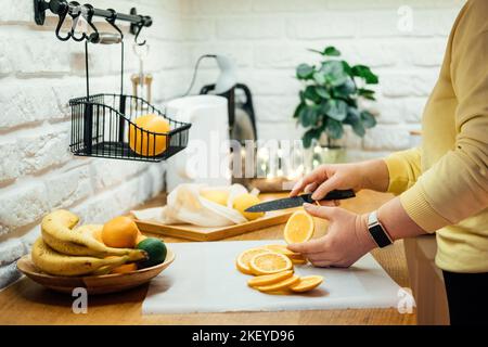 How to Dry Orange Slices for Holiday Decor. Process of Drying Orange Slices in the Oven. Woman cutting slices of orange and citrus fruits for drying Stock Photo