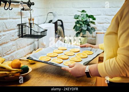 How to Dry Orange Slices for Holiday Decor. Process of Drying Orange Slices in the Oven. Woman cutting slices of orange and citrus fruits for drying Stock Photo