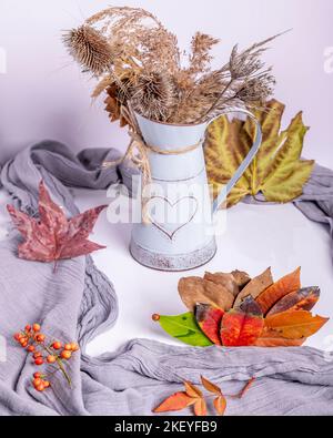 A funny hedgehog made with dry autumn leaves in a composition with dried flowers, red berries and other colorful leaves Stock Photo
