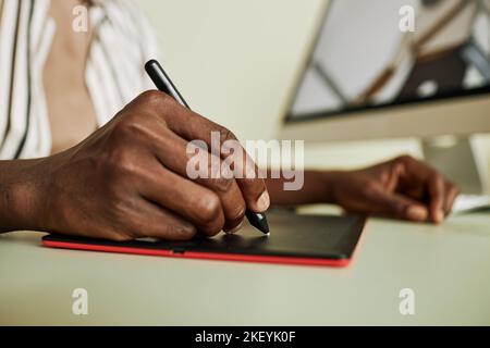 Hand of young African American designer of digital drawing using graphic pen and tablet while creating new artworks on computer Stock Photo