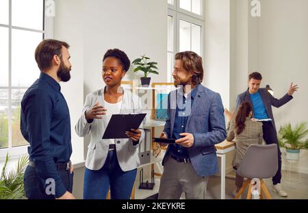 Three work colleagues are discussing joint business project together at meeting in office. Stock Photo