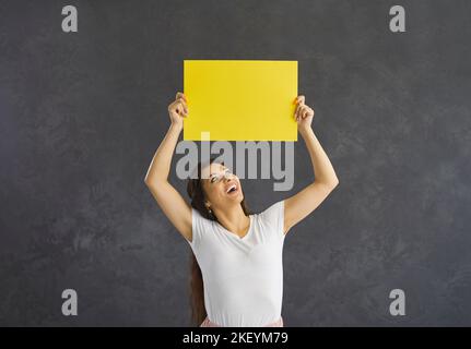 Smiling Latin woman show yellow mockup banner Stock Photo