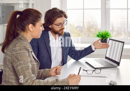 Business adviser talking to his client and showing spreadsheets on laptop computer Stock Photo