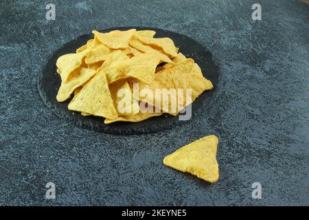 Mexican corn chips nachos on black stone or on the black concrete background. Stock Photo