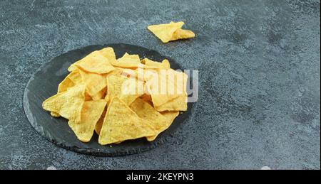 Mexican corn chips nachos on black stone or on the black concrete background. Stock Photo