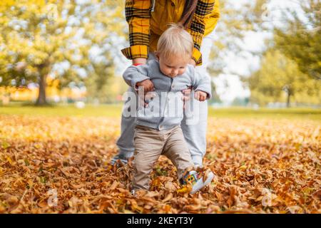 Young mother teaching her little child to walk Little baby first steps, family time concept Stock Photo