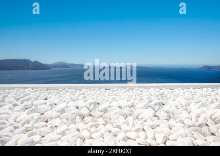 Traditional white architecture on Santorini island, Greece. White pebbles over blue sea view, idyllic calming travel landscape. Beautiful white decor Stock Photo
