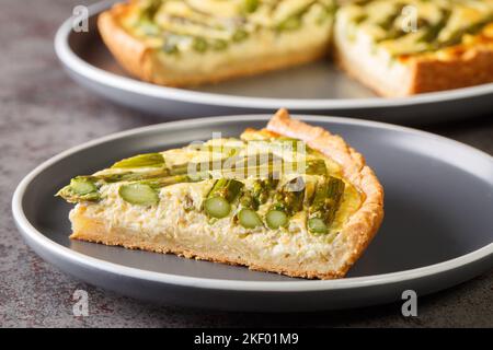 Homemade vegetarian creamy asparagus tart close-up in a plate on the table. Horizontal Stock Photo
