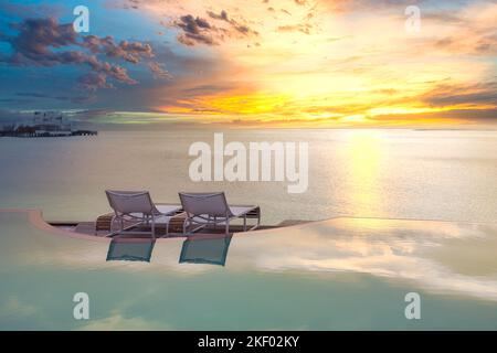 Seascape view under sunset light with dining table with infinity pool around. Romantic tropical getaway for two, couple concept. Chairs, food romance Stock Photo