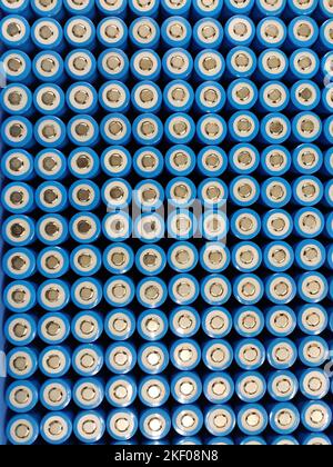 A close-up image of a grid of cylindrical lithium-ion batteries. The batteries are arranged in rows and columns, with their blue plastic casings. Stock Photo