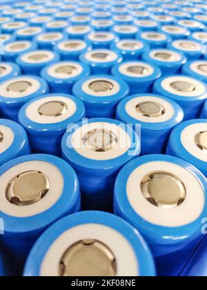 Close-up of blue cylindrical lithium batteries, featuring positive terminal tops, arranged in a precise, repeating grid. Stock Photo