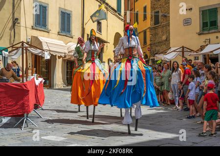 Street performers on stilts on Piazza Luca Signorelli in hilltop town of Cortona in Tuscany, Italy Stock Photo