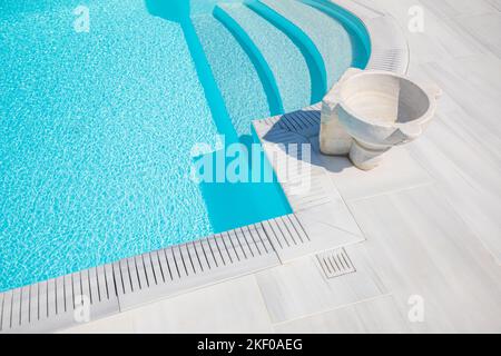 Swimming pool with stair and elegant pave stone steps into azure water. Luxury style poolside with marble vase under sunny weather. Summer outdoor spa Stock Photo